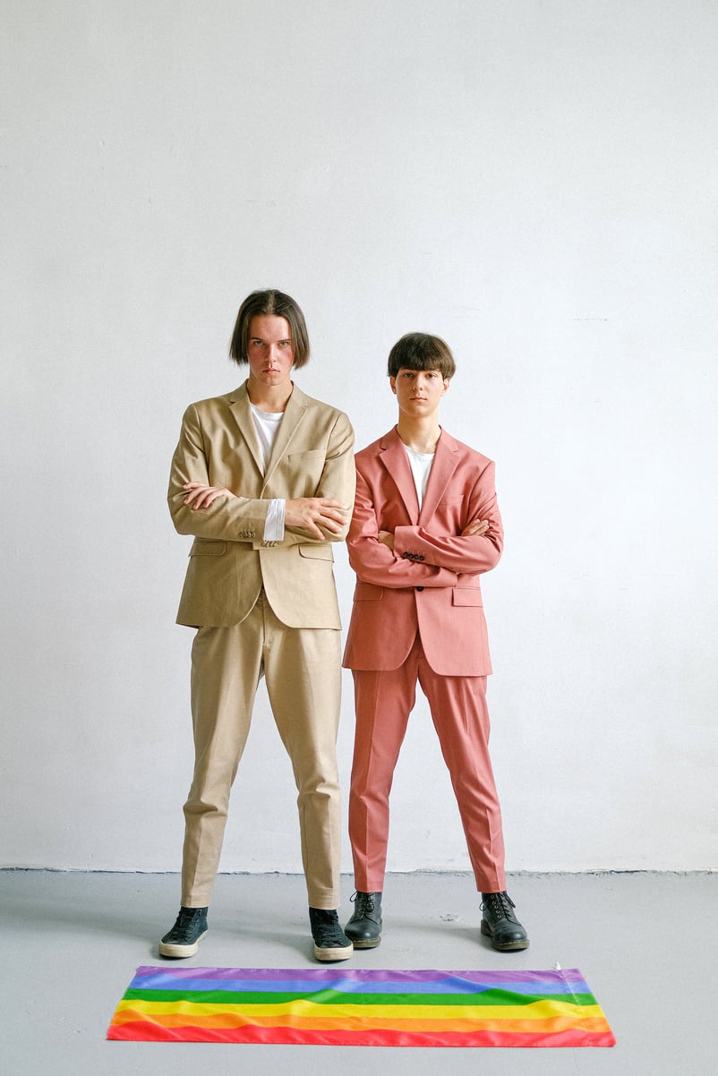 Two Men Standing Next to a Gay Pride Flag